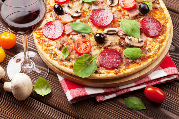 Italian pizza with pepperoni, tomatoes, olives, basil and red wi Stock photo © karandaev