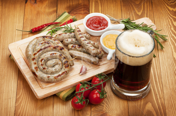 Grilled sausages with ketchup, mustard and mug of beer Stock photo © karandaev