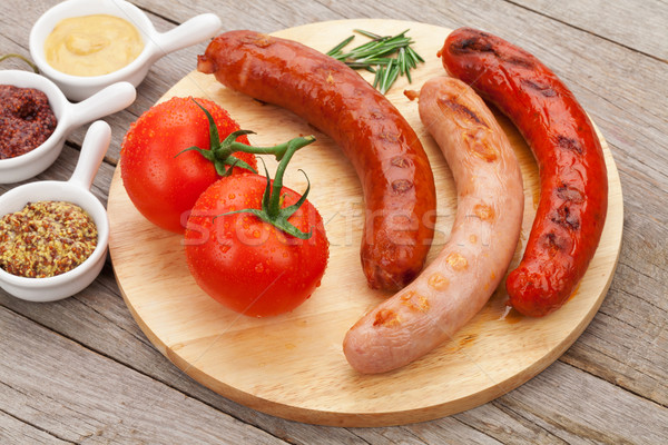 Various grilled sausages with condiments and tomatoes Stock photo © karandaev