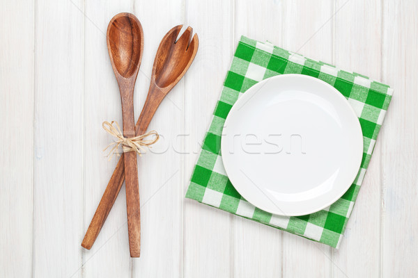 Empty plate and kitchen utensils over wooden table background Stock photo © karandaev