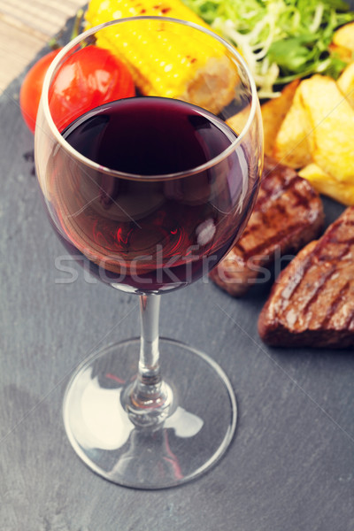 Red wine glass and steak with grilled potato, corn, salad Stock photo © karandaev