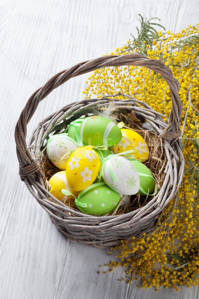 Colorido ovos de páscoa cesta flores mesa de madeira primavera Foto stock © karandaev