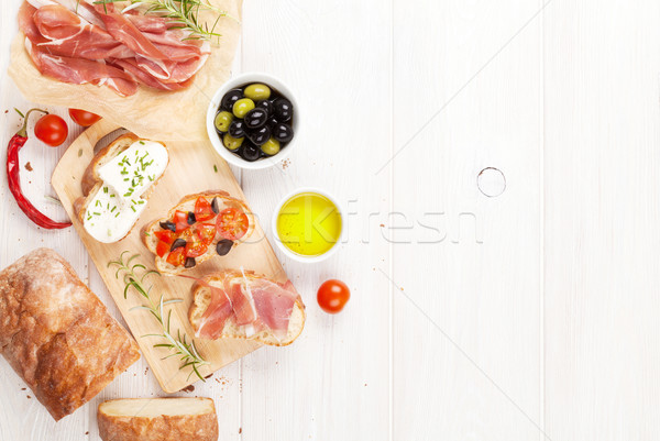 Bruschetta with cheese, tomatoes and prosciutto Stock photo © karandaev
