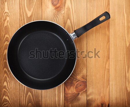 Frying pan on wooden table Stock photo © karandaev