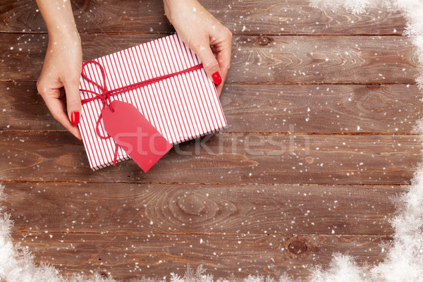 Female hands holding gift above wooden table Stock photo © karandaev