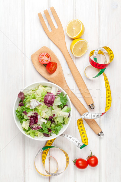 Fresh healthy salad, utensils and tape measure over white wooden Stock photo © karandaev