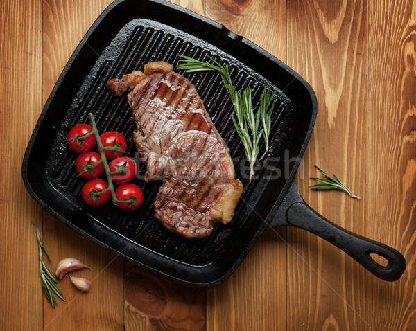 Lombo de vaca bife alecrim tomates cereja frigideira mesa de madeira Foto stock © karandaev