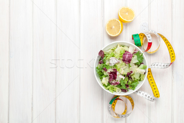 Fresh healthy salad, utensils and tape measure over white wooden Stock photo © karandaev