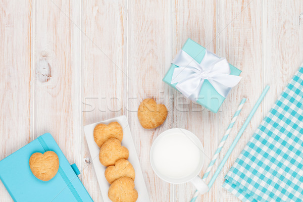 Cup of milk, heart shaped cookies, gift box and notepad Stock photo © karandaev