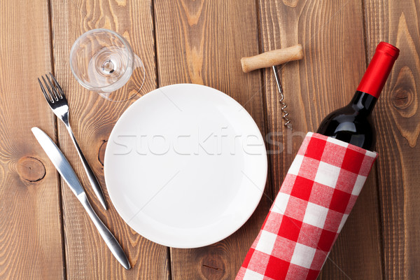Table setting with empty plate, wine glass and red wine bottle Stock photo © karandaev