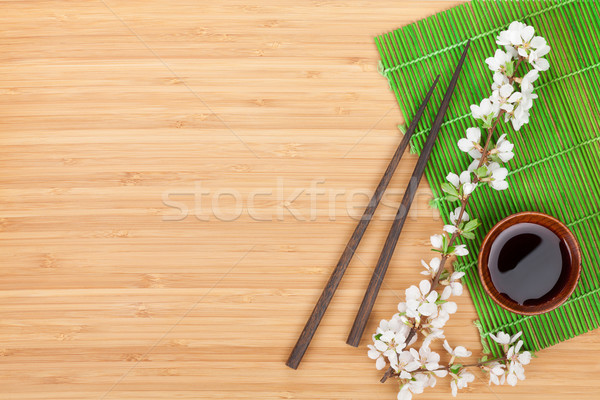 Chopsticks, sakura branch, soy sauce and bamboo mat Stock photo © karandaev