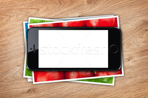 Phone with blank screen over stack of printed pictures collage Stock photo © karandaev