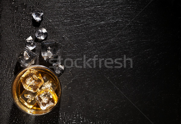 Stock photo: Glass of whiskey with ice on black stone table