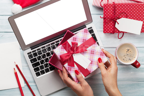 Female working on laptop and wrapping gifts Stock photo © karandaev