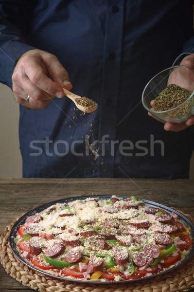 Man in a blue shirt sprinkle with spice pizza from a glass sauser Stock photo © Karpenkovdenis