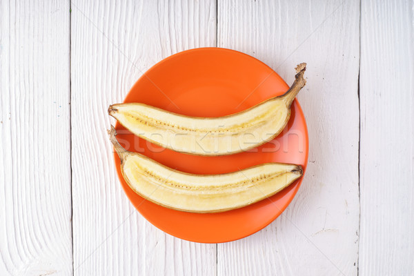 Banana halves lie on orange plate Stock photo © Karpenkovdenis