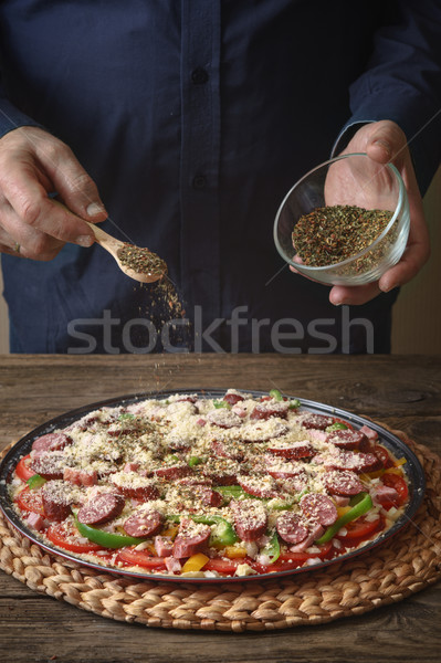 Man sprinkle with spice pizza from a glass sauser Stock photo © Karpenkovdenis