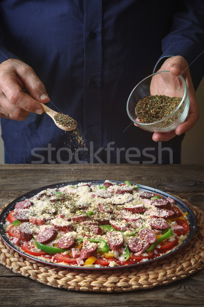 Man sprinkle with spice pizza from a glass sauser Stock photo © Karpenkovdenis