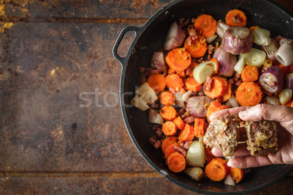 Adding  fried meat in the pan with carrots and shallot top view Stock photo © Karpenkovdenis
