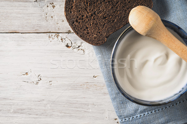 Sour cream on the ceramic dish with bread on the white wooden table top view Stock photo © Karpenkovdenis