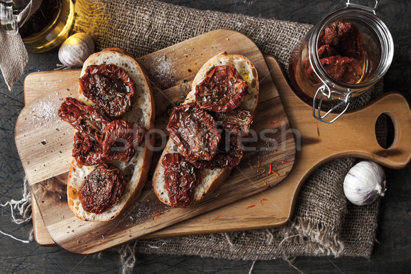 Sun-dried tomatoes on the white bread on the wooden board Stock photo © Karpenkovdenis
