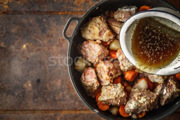 Adding broth in the pan with meat and vegetable top view Stock photo © Karpenkovdenis