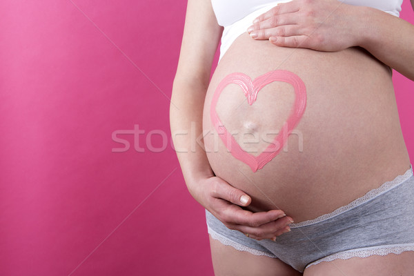 Closeup of a pregnant woman with pink heart on her belly Stock photo © kb-photodesign