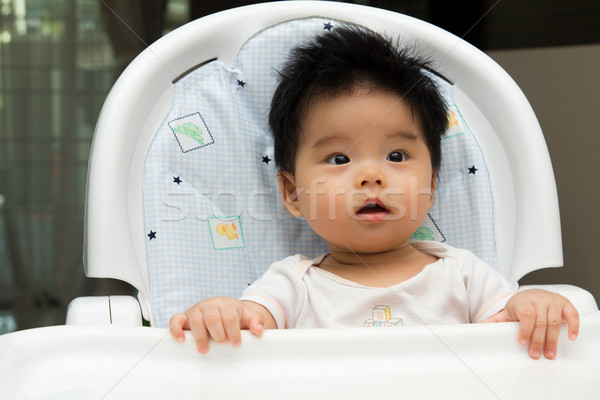 Stock photo: Little baby sits on a high chair