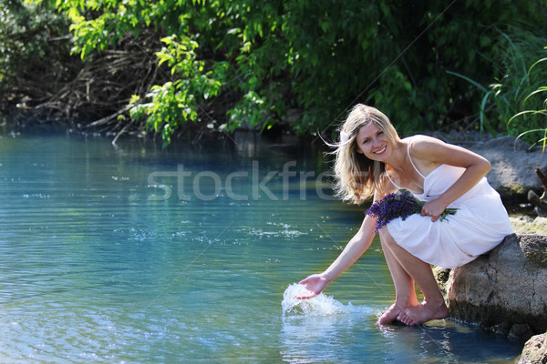 Stock photo:  girl squirting water at the lake