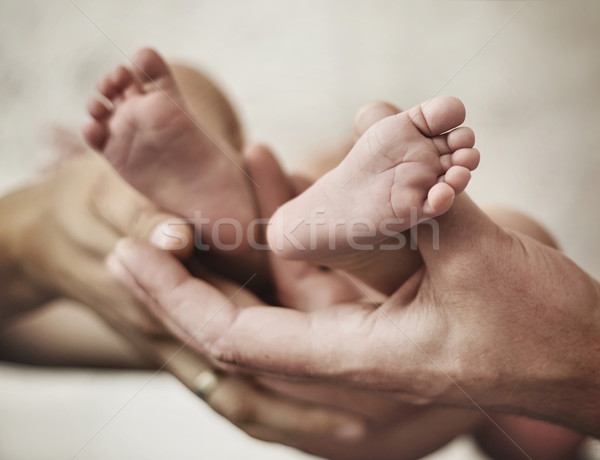 Conceptual picture of parents golding a baby's feet Stock photo © konradbak