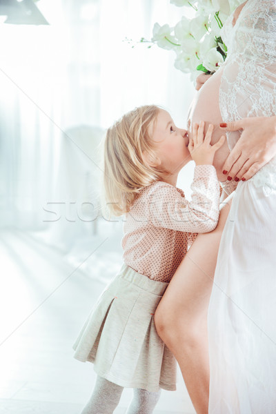 Little daughter kissing her mother's belly Stock photo © konradbak