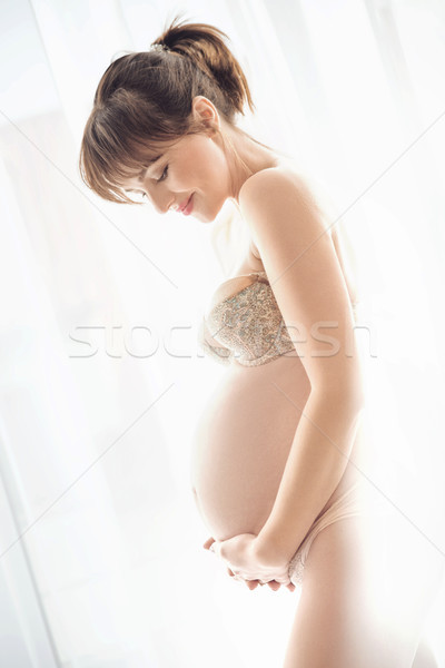 Stock photo: Portrait of a charming pregnant woman stroking a belly