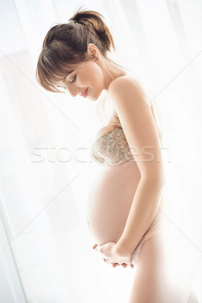 Portrait of a charming pregnant woman stroking a belly Stock photo © konradbak