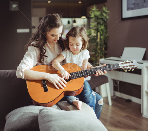 Stock photo: Mother and daughter playing a guitar