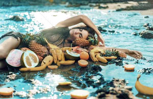 Brunette model posing with lots of healthy tropical fruit Stock photo © konradbak