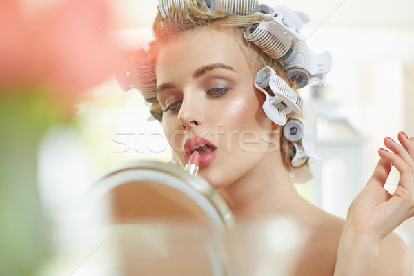 Blond woman putting on a lipstick Stock photo © konradbak