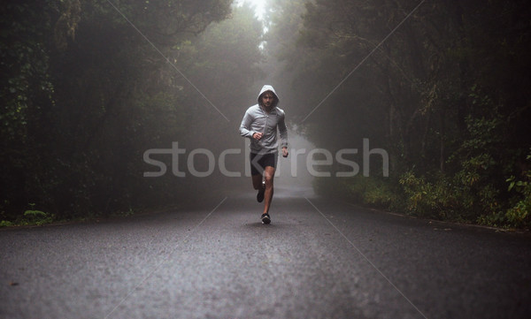 Portrait of a young athlete running on the road Stock photo © konradbak