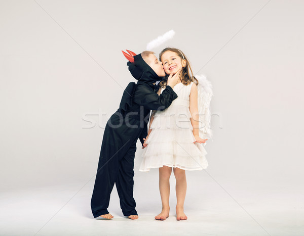 Little devil-boy kissing his angel friend Stock photo © konradbak