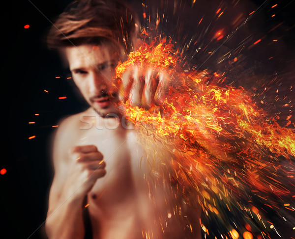 Handsome athlete punching with flame around his fist Stock photo © konradbak