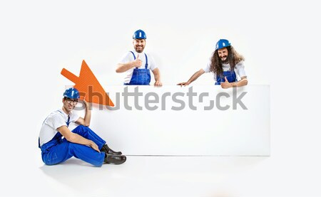 Three handsome craftsmen holding an empty white board Stock photo © konradbak