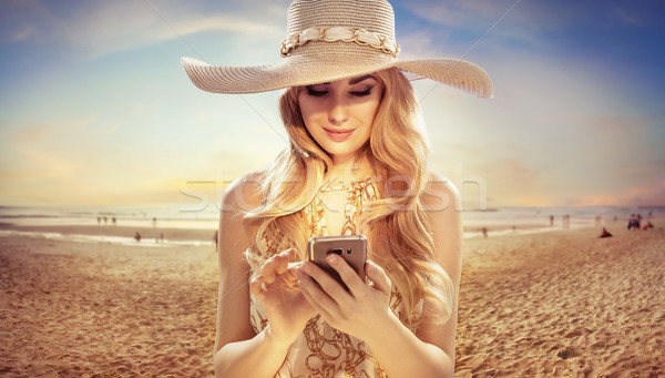 Attractive blonde texing on sunny beach Stock photo © konradbak