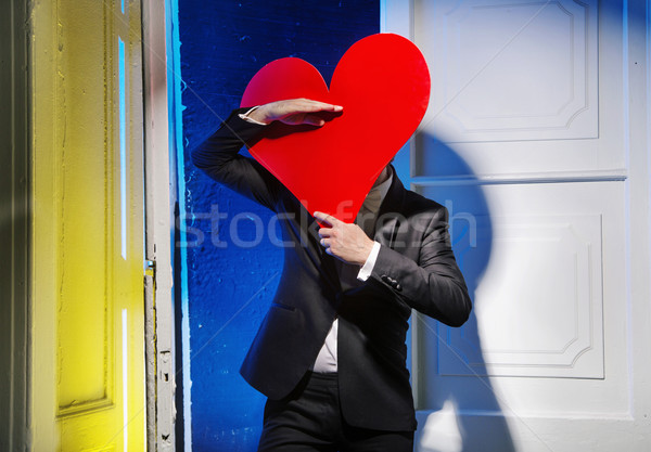 Cheerful man hiding himself behind a heart Stock photo © konradbak