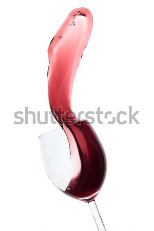 Stock photo: red wine splashing out of a glass, isolated on white