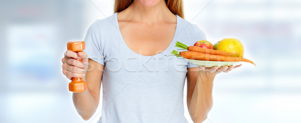 Stock photo: Beautiful lady with dumbbell and food