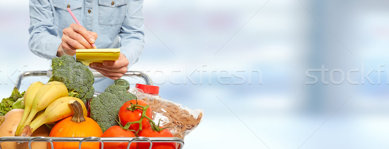Woman with shopping cart writing on notepad. Stock photo © Kurhan