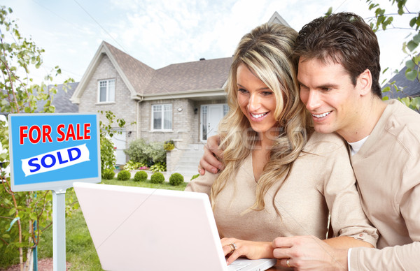 Stock photo: Couple with laptop near new house.