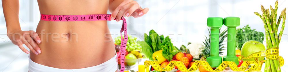 Woman abdomen with measuring tape over vegetables background. Stock photo © Kurhan