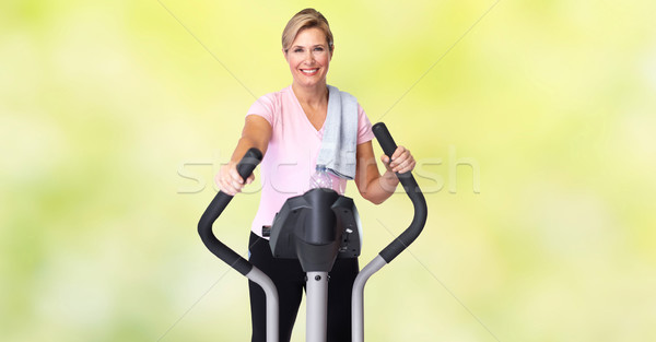 Mature woman doing exercise on elliptical trainer. Stock photo © Kurhan