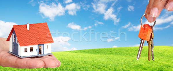 Stock photo: Hand with a little house and keys.