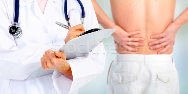Stock photo: Hands of a medical doctor. Back pain.